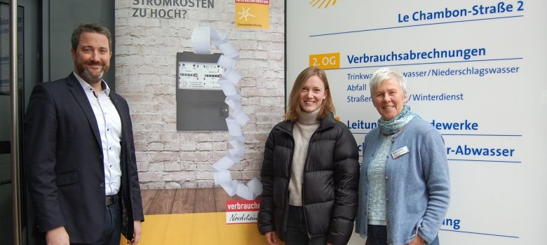 Bürgermeister Marco Diethelm, Klimaschutzmanagerin Caroline Hüttemann und Energieberaterin Brigitte Topmöller vor einem Werbeplakat der Verrbaucherzentrale