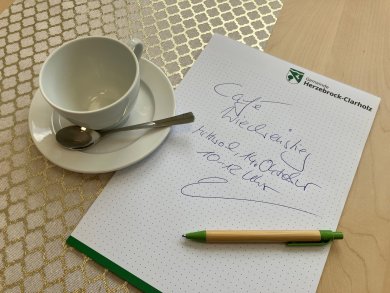 Kaffeetasse und Schreiblock mit Kugelschreiber