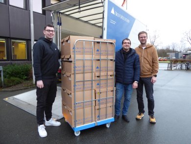 Mitarbeiter mit Kisten vor Lastwagen