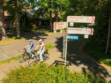 zwei Radfahrende und Hinweisschilder