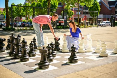 Mann und Frau spielen Schach mit großen Figuren