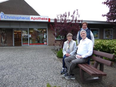drei Personen auf der Ruhebank vor der Apotheke