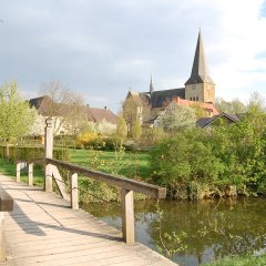 Blick auf den Kirchturm von St. Christina mit Holzbrücke im Vordergrund